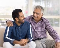 Senior man joyfully talking with a younger man, highlighting emotional connection and purpose in senior retirement homes through volunteering.