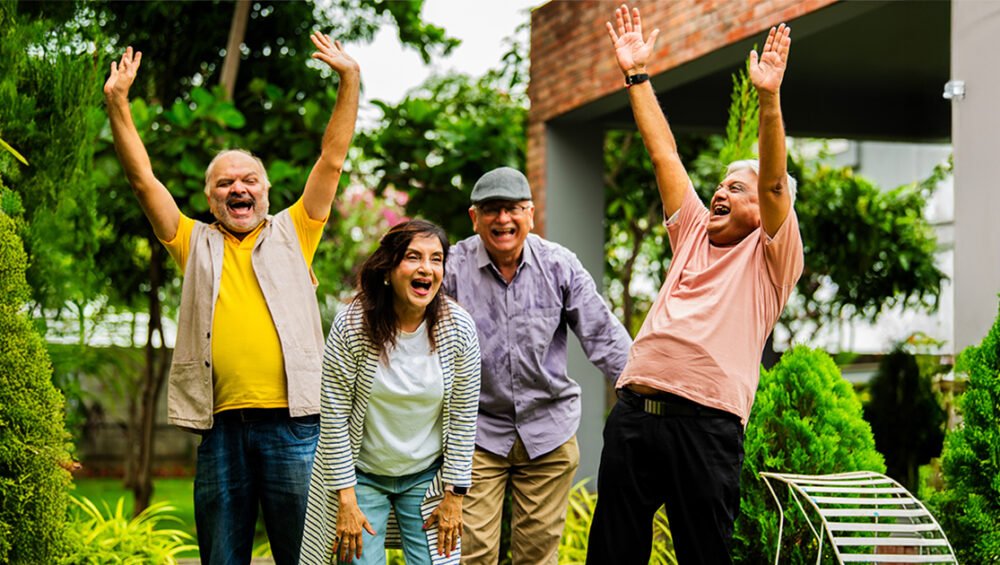 A joyful group of seniors enjoying outdoor activities in a green garden, representing the lively community atmosphere offered by affordable senior living options.