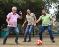 Three seniors playing football in a park, staying active and energetic—showcasing the importance of physical activity for seniors in retirement homes offered by Saral Satya Legacy.