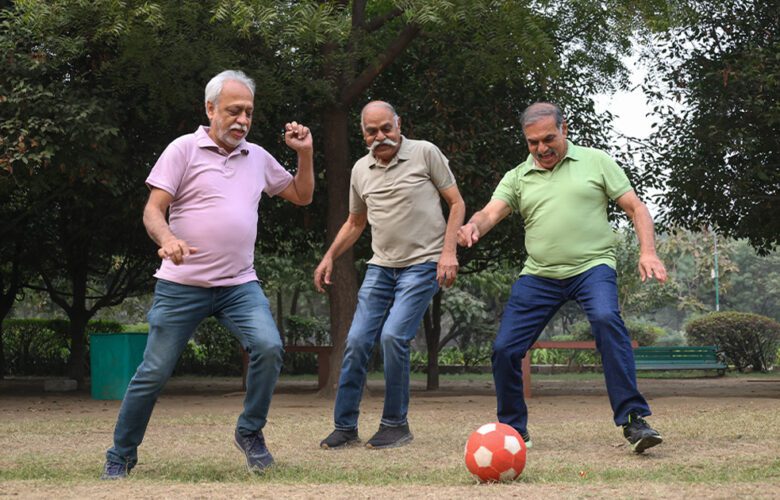 Three seniors playing football in a park, staying active and energetic—showcasing the importance of physical activity for seniors in retirement homes offered by Saral Satya Legacy.