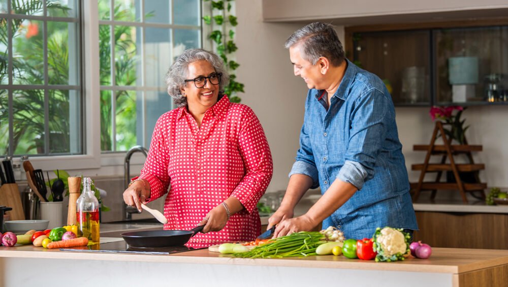Senior couple preparing healthy winter meals in a modern kitchen, highlighting nutrition and diet tips for seniors living in retirement communities at Saral Satya Legacy.