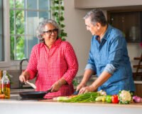 Senior couple preparing healthy winter meals in a modern kitchen, highlighting nutrition and diet tips for seniors living in retirement communities at Saral Satya Legacy.