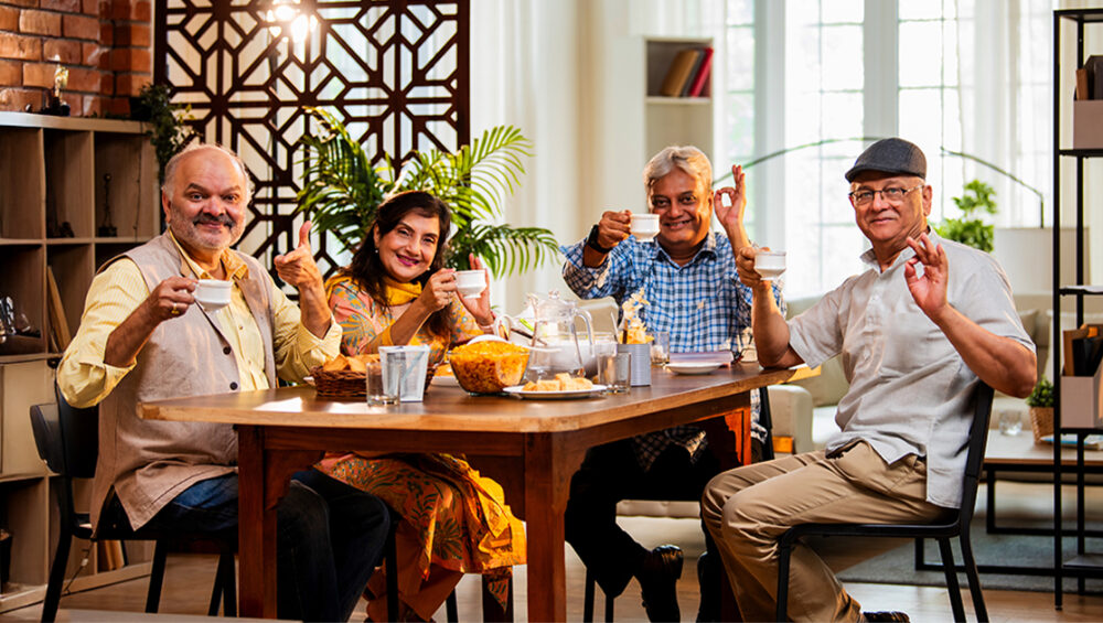 Group of seniors enjoying tea together at a dining table, reflecting social and community life in rental retirement homes at Saral Satya Legacy.