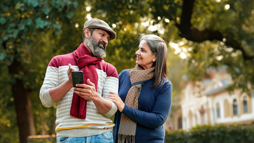Senior couple reviewing information on a mobile phone while discussing options for choosing an old age home in Gurugram.