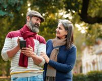 Senior couple reviewing information on a mobile phone while discussing options for choosing an old age home in Gurugram.
