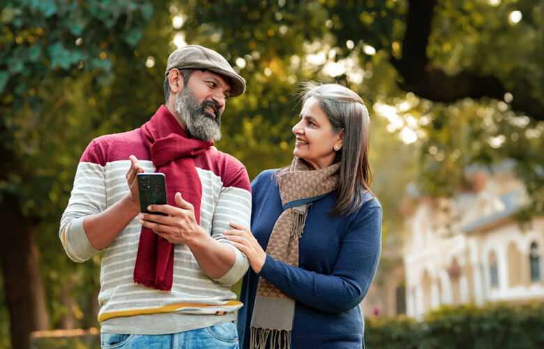Senior couple reviewing information on a mobile phone while discussing options for choosing an old age home in Gurugram.