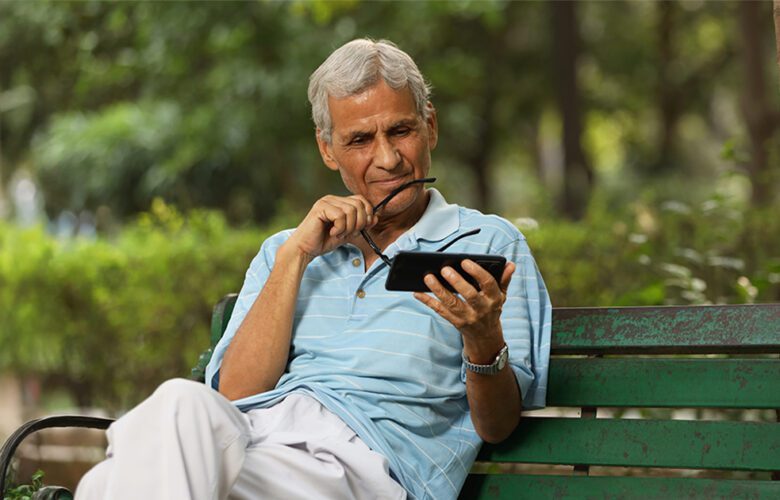 Senior man using a smartphone to search for assisted living facilities nearby, highlighting easy and convenient senior care options by Saral Satya Legacy.